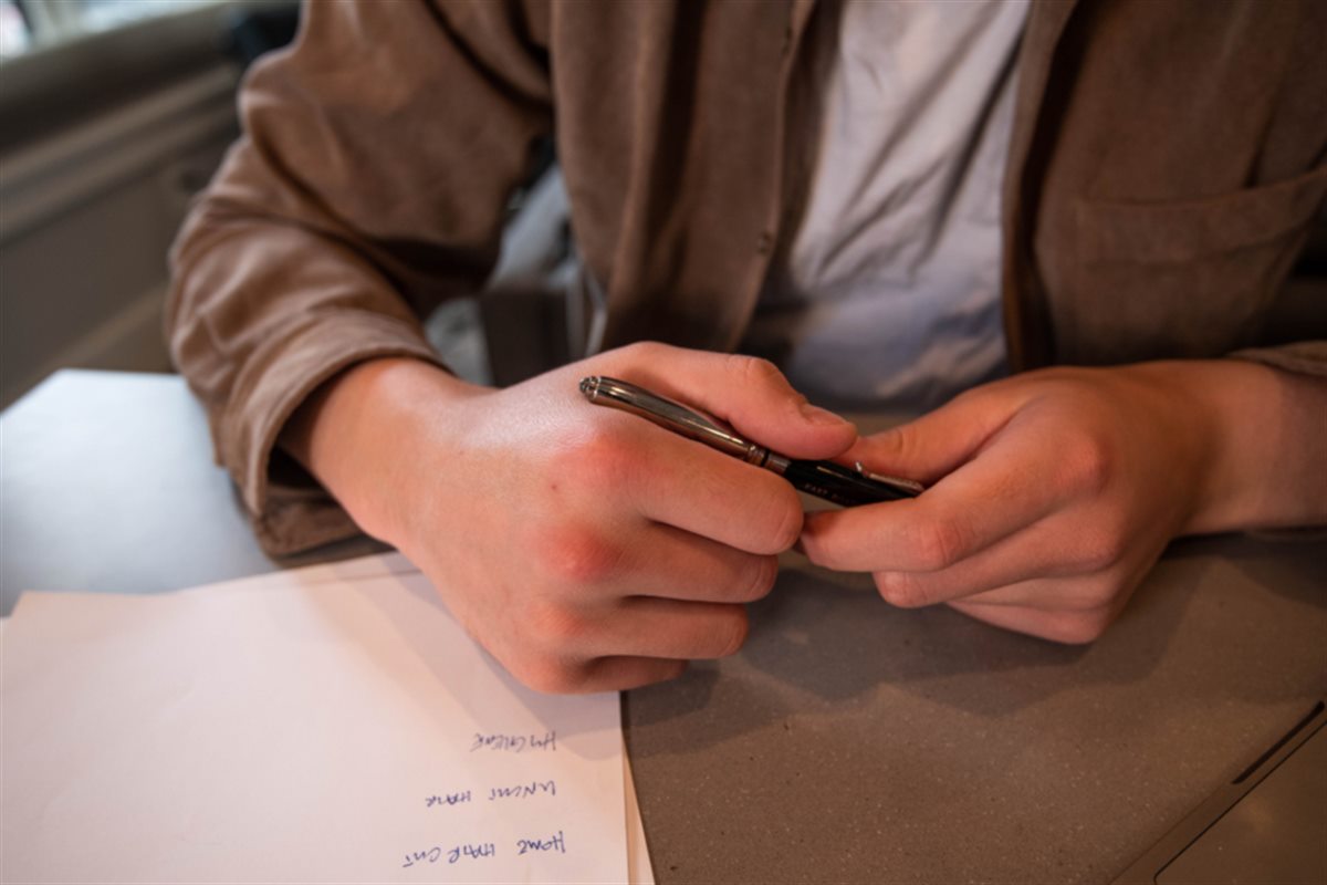 Hands writing a list of jobs on paper at a table