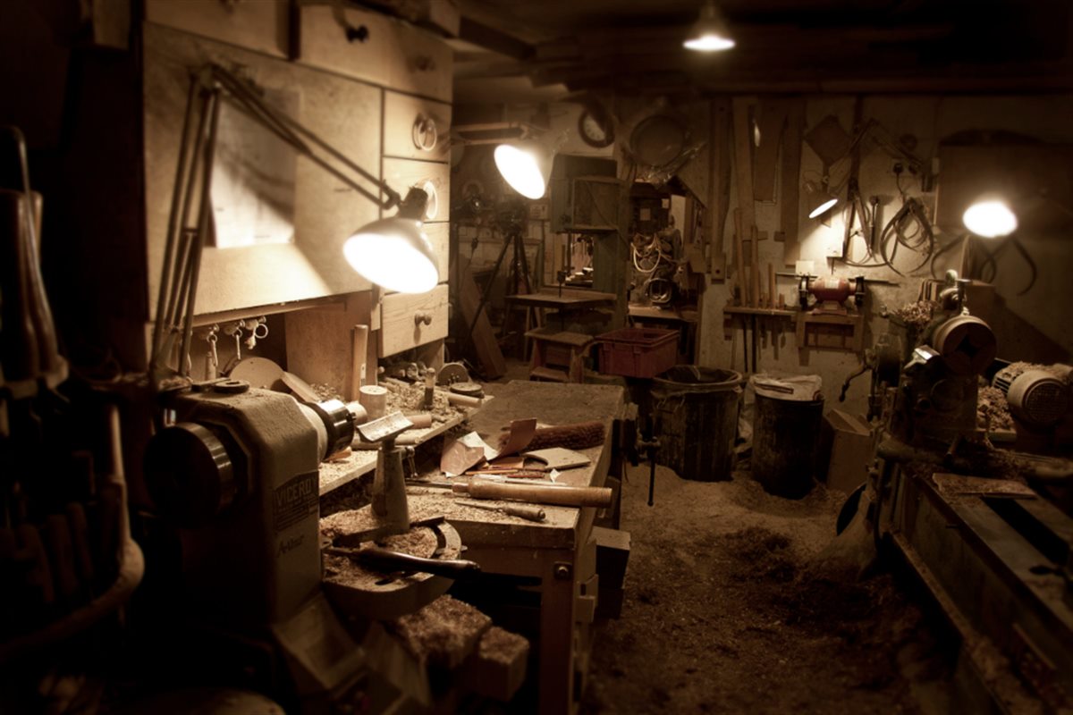 A workshop bench with hand tools under a work lamp